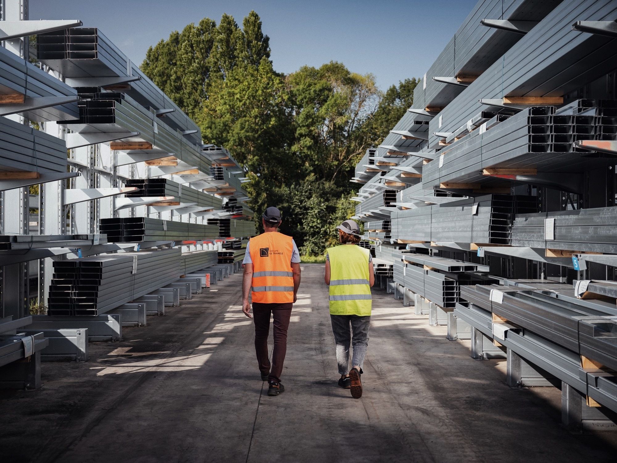 2 hommes de dos dans une zone de stockage de structure métallique, panne métallique pour la construction de panneau solaire et structure photovoltaïque