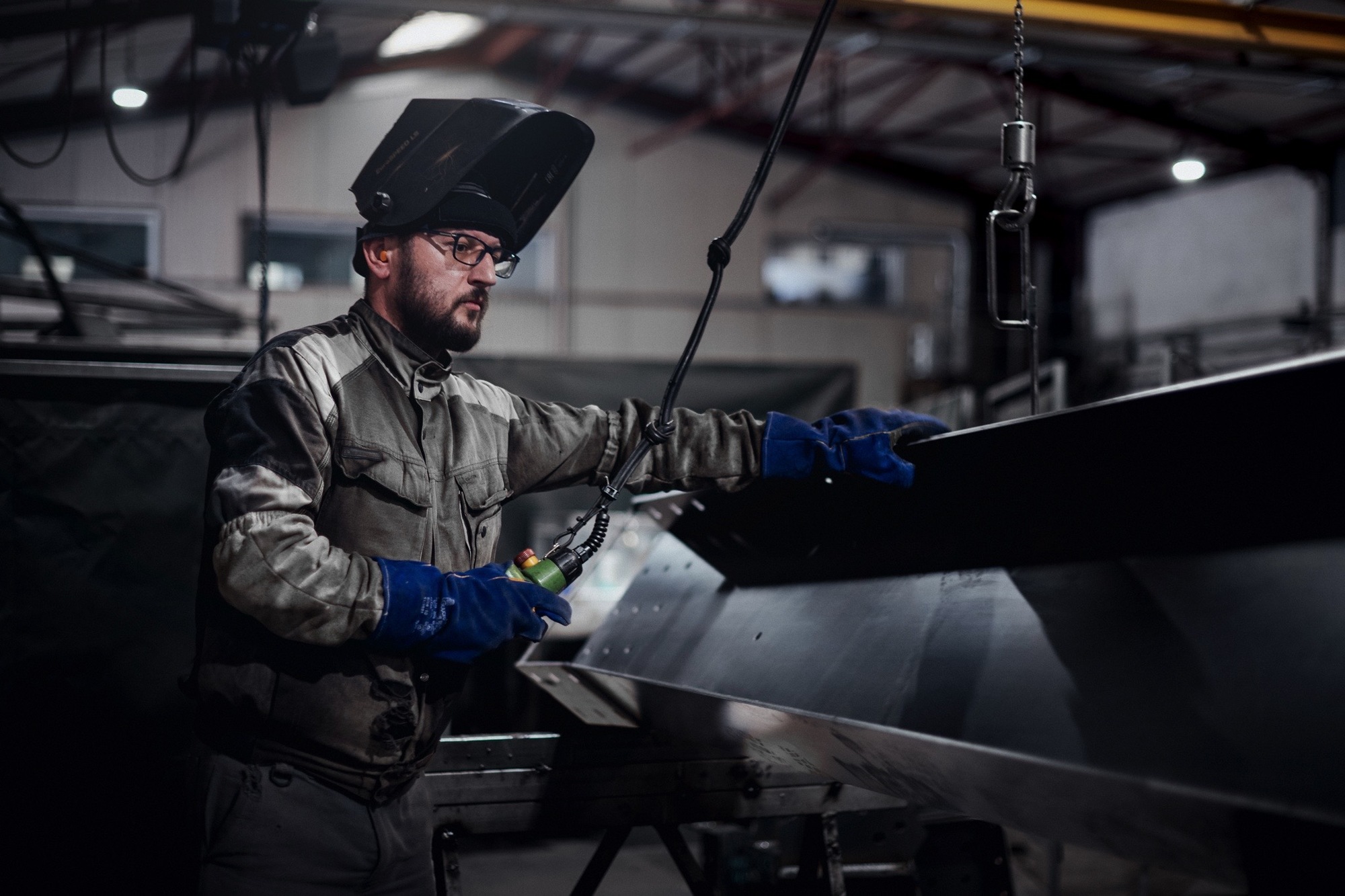 Un homme qui soude au coeur de l'atelier de production du Groupe Le Triangle en train de travailler sur une structure pour ombrière solaire