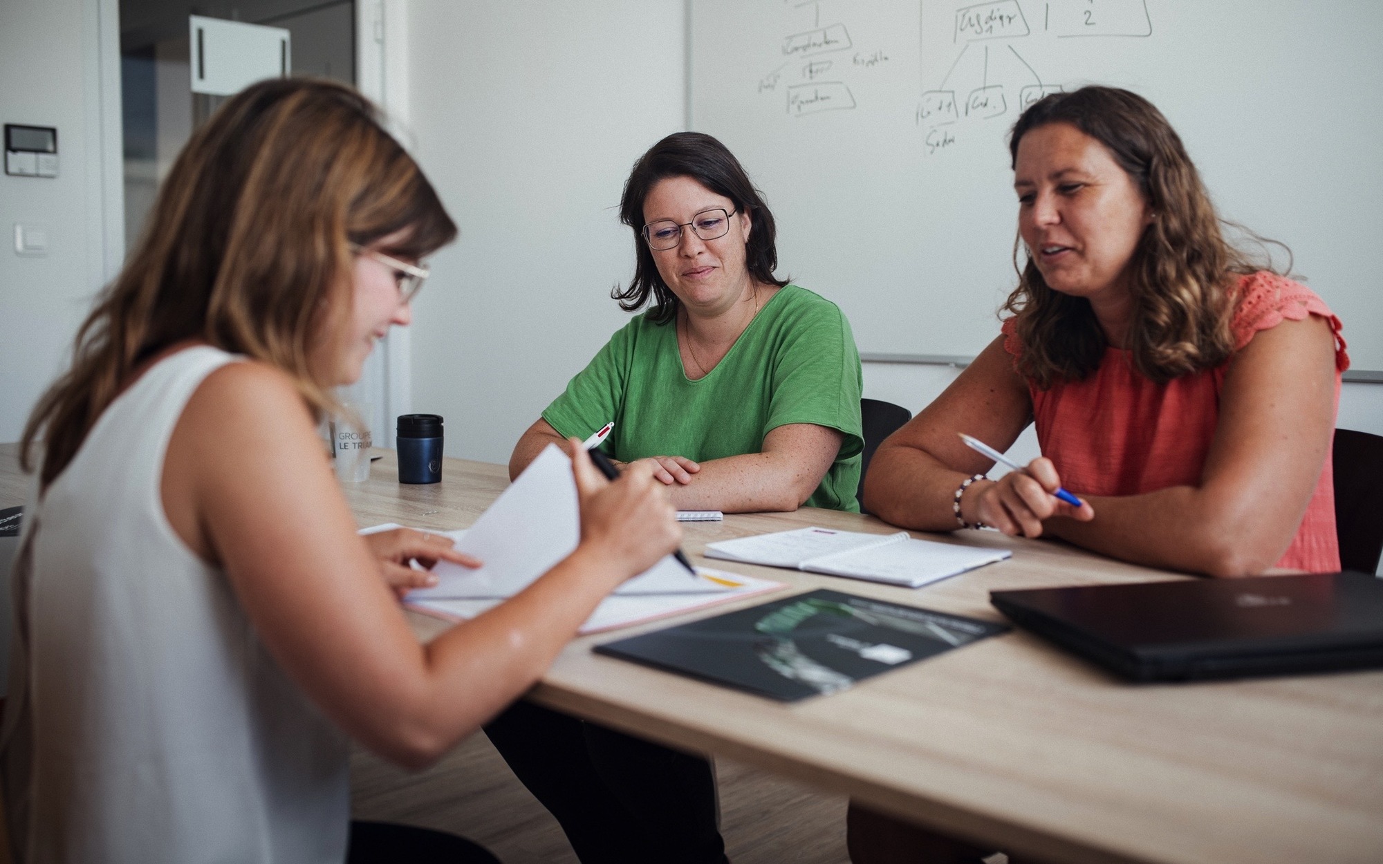 Collaborateurs d'un service de fonction support du Groupe Le Triangle en train d'échanger sur une plaquette métier