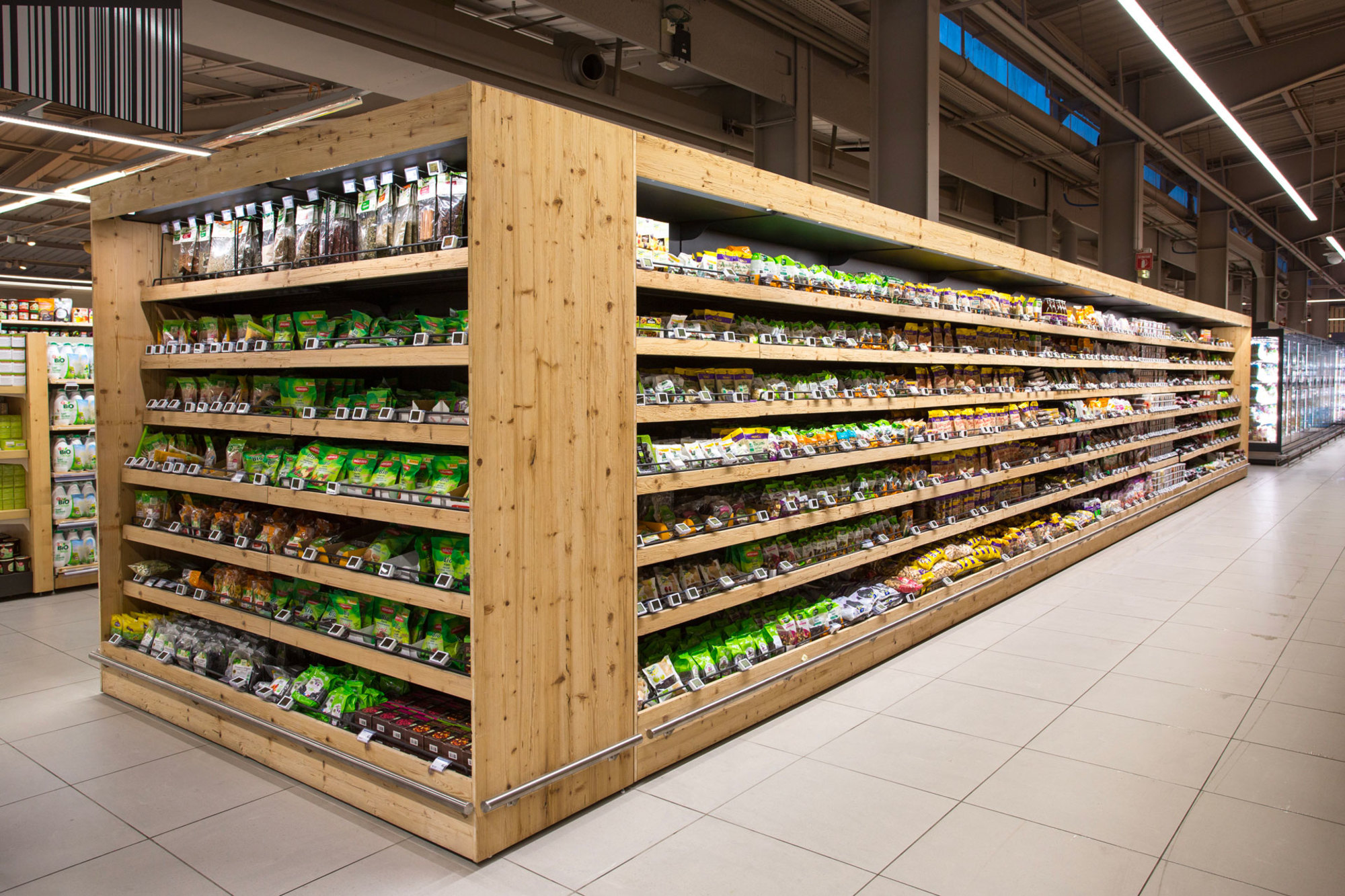 Allée dans un supermarché avec des thés emballés, des cafés et autres produits secs sur un mobilier réalisé en France par Triangle mobilier.