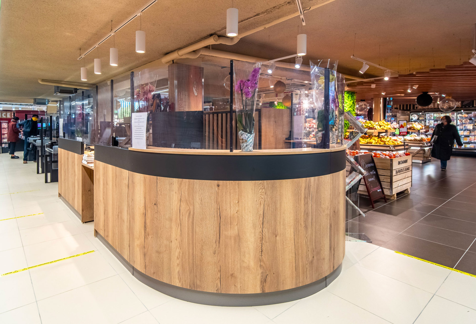 Comptoir de service client arrondi dans un supermarché avec un design en bois et noir Made In France par TriangleMobilier, concepteur fabricant de mobilier pour GMS.