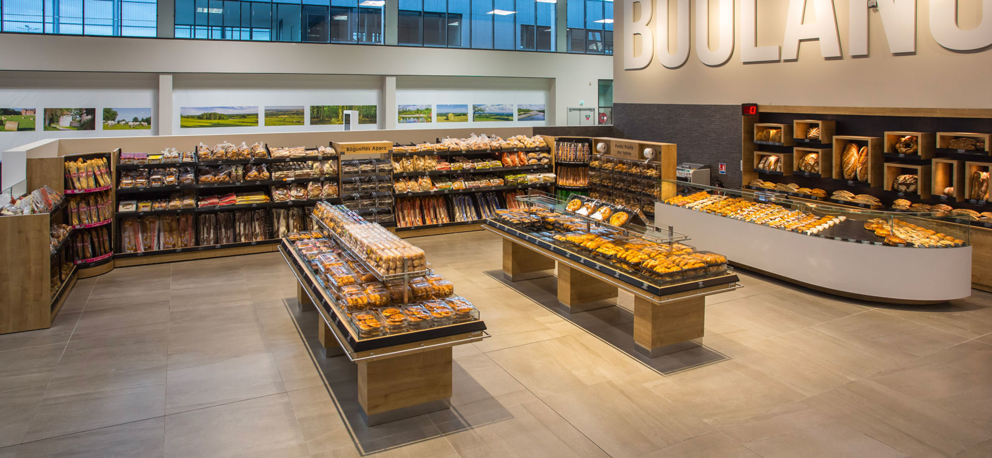 Section boulangerie d'une Réalisation Triangle Mobilier dans un supermarché présentant pains, pâtisseries et baguettes.