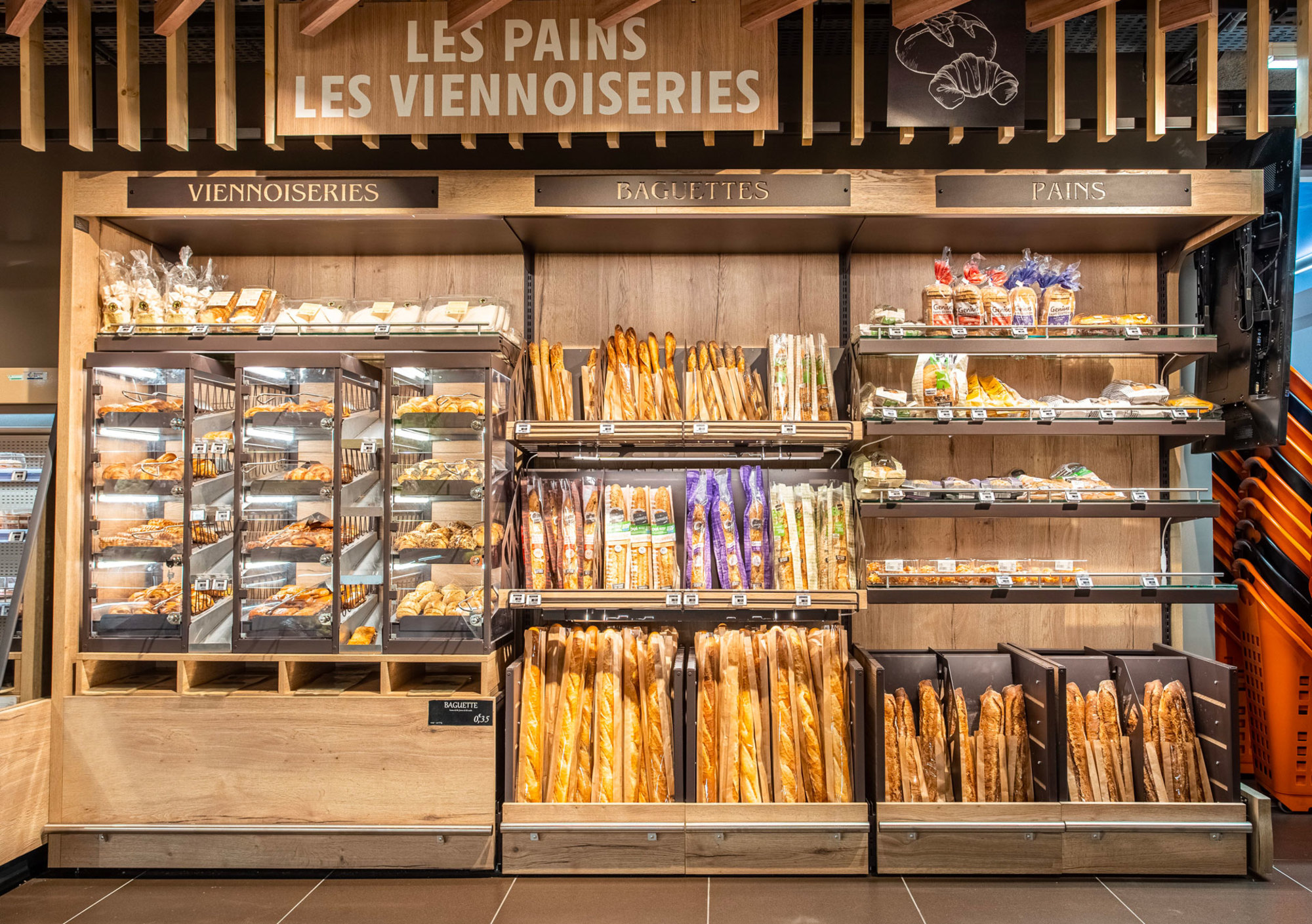 Section boulangerie d'une Réalisation Triangle Mobilier dans un supermarché présentant pains, pâtisseries et baguettes.