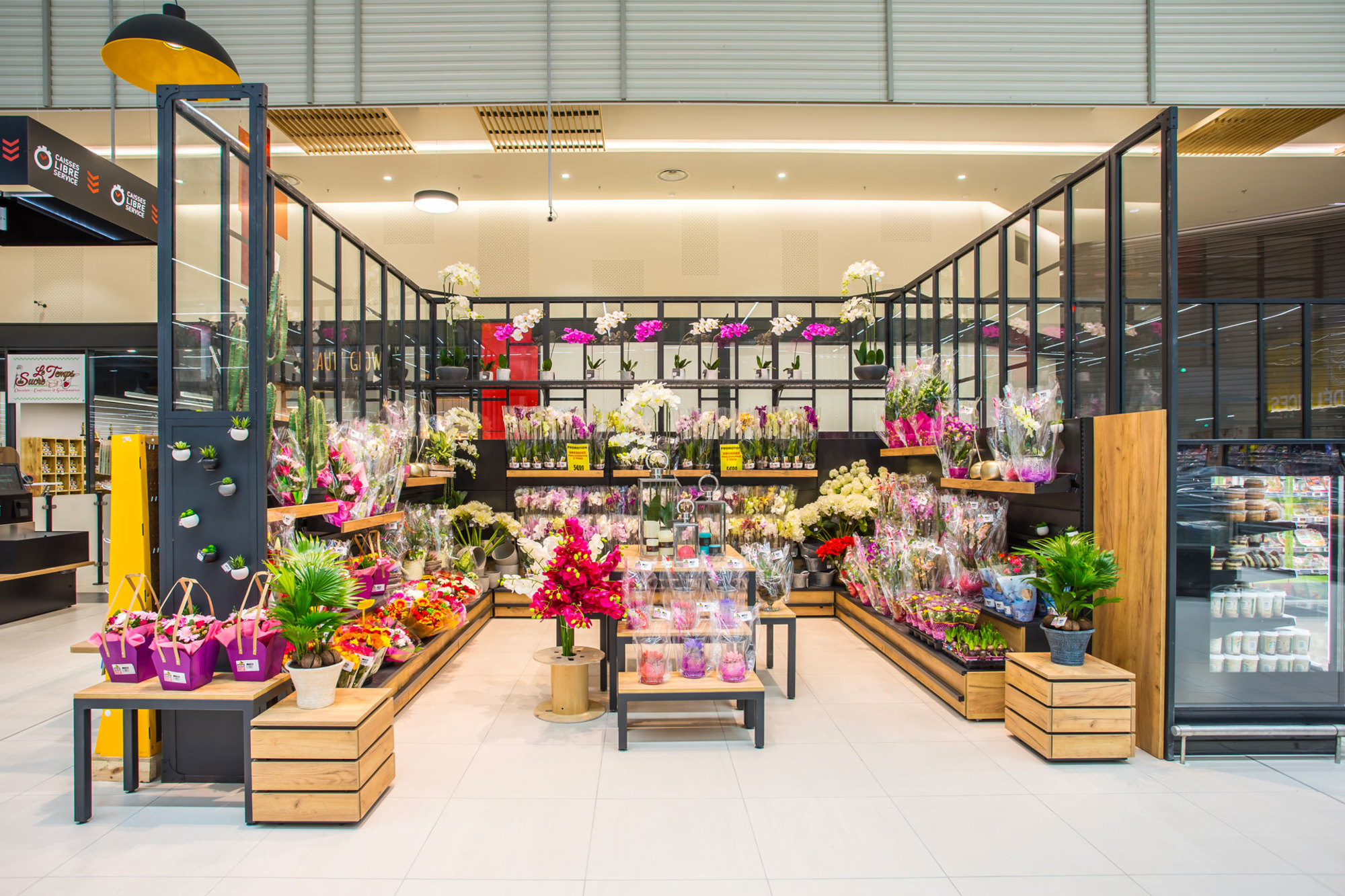Section fleuriste à l'intérieur d'un supermarché avec une variété de bouquets et de plantes.