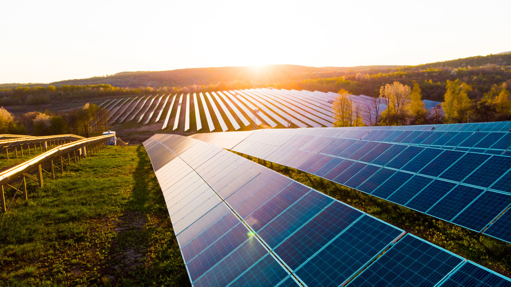 Un paysage rural au lever du soleil avec un grand champ solaire en premier plan.