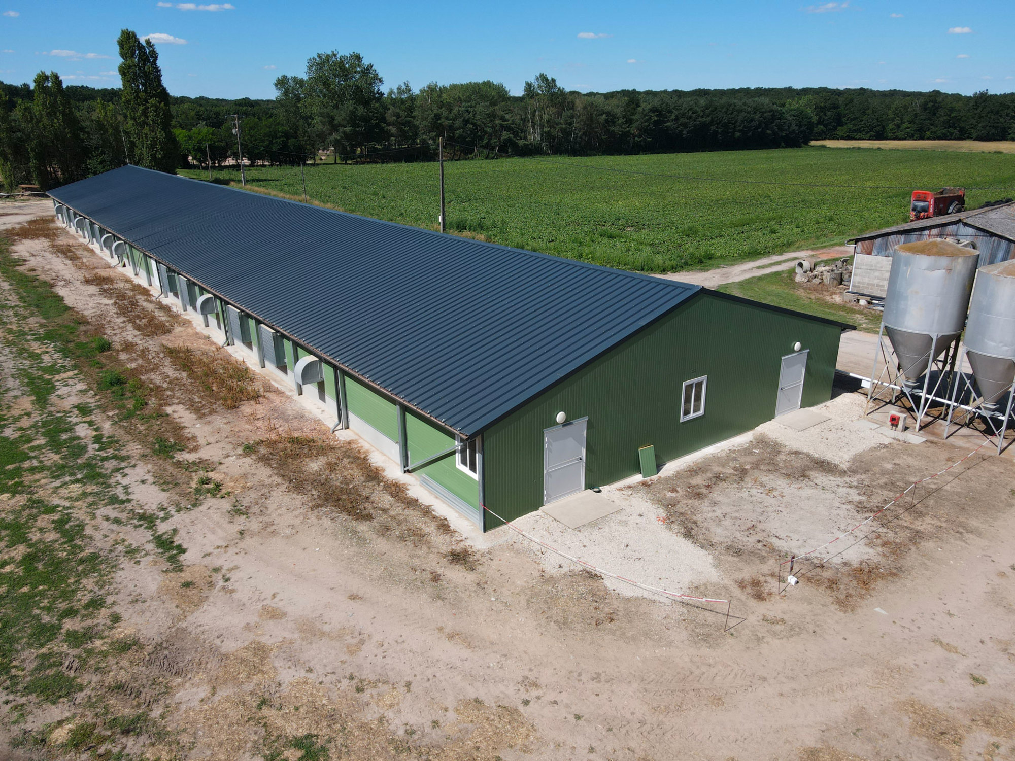 Structure moderne d'élevage de volailles sous un abri solaire, montrant l'expertise de Le Triangle dans la construction de bâtiments agricoles solaires.