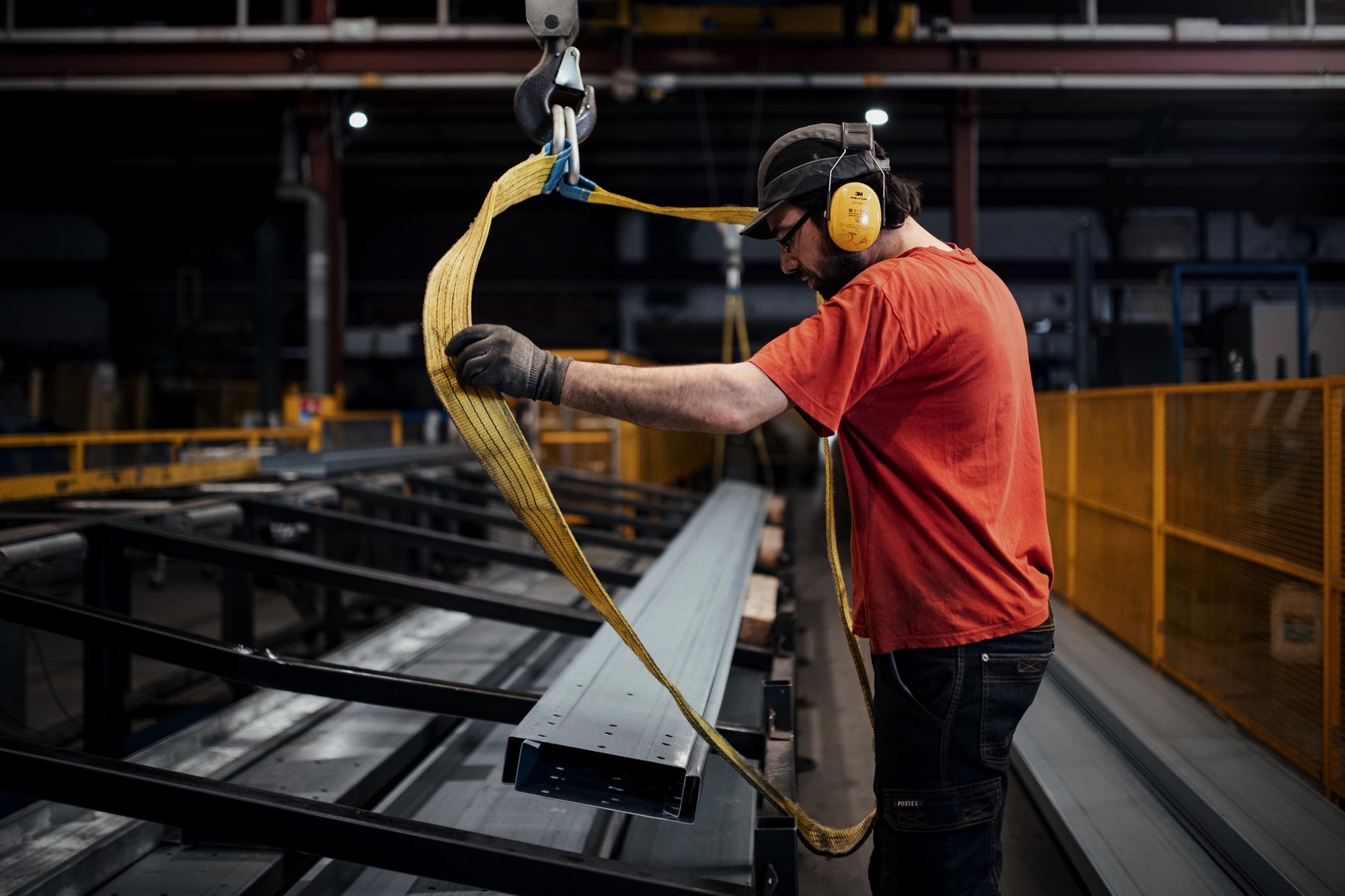 1 homme manipulant des morceaux de panne métallique pour la construction de panneau solaire chez le Groupe Le triangle